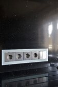 Steckdosenleiste in schwarzer Rückwand einer modernen Küche