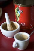 Tine of coffee next to pestle and mortar