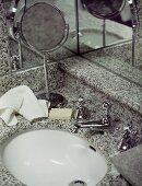 Granite wash hand basin, mirrored walls and a shaving mirror with hand towel and soap.