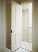 A view through an open, painted panelled interior door into a neutral hallway