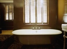 A detail of a traditional, bathroom, a free standing roll top bath, window shutters