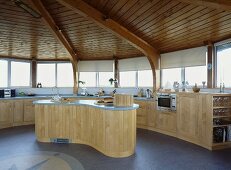 Kreisförmiger Raum mit Holzdecke und offene Küche mit geschwungener Kochinsel