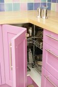 Salz und Pfeffermühle auf Arbeitsplatte über offenem Küchendrehschrank mit rosa Holzfront