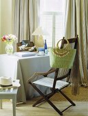 Esszimmer mit Meeresblick mit antikem Klappstuhl, daran hängender grüner Tasche und einem Tisch mit pastellblauer Tischdecke