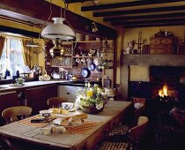 Viktorianische Lampe aus Messing und Glas über einem Tisch aus Kiefer Tisch und ein Kamin in einer Landhausküche