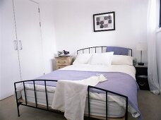 A double bed with a metal bedstead in a white bedroom