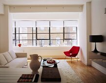 Offener moderner Wohnraum mit hellem Sofa und rotem Sessel im Stilmix
