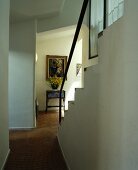 Gemauerter Treppenaufgang mit schlichtem Handlauf und Boden aus Terracotta-Kleinstein in weisser Diele