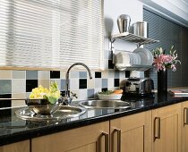 Rundes Edelstahlbecken mit Abtropfschale in Granitarbeitsfläche unter geschlossener Metalljalousie in moderner Küche