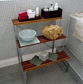 Badezimmerregal aus Metallgestell mit Holzlatten vor hellgrauen Mosaikfliesen
