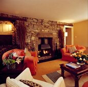 Rustikale Natursteinwand mit brennendem Kamin in traditionellem Wohnzimmer