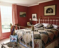 Ein viktorianisches schmiedeeisernes Bett mit Messing in einem roten Schlafzimmer