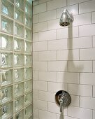 Eine weißgeflieste Dusche mit einer Wand aus Glasbausteinen
