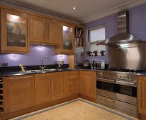 Eine in violette gestrichen moderne Küche mit Holz-Einheiten und einen Edelstahl Herd