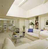 weiße Sofas und ein Glastisch stehen in einer modernen und offenen Wohnung