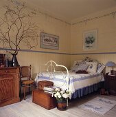 Ein traditionelles Landhaus-Schlafzimmer in dem ein Eisenbett und diverse Holzmöbel stehen