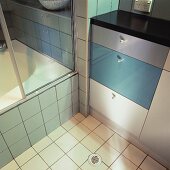 Nahaufnahme des weißen Fliesenbodens und der grau-türkisen Schubladen des modernen Badezimmers