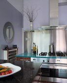 Moderne Küche mit Edelstahlgeräten und Spritzschutz aus Edelstahl vor lavendelfarben gestrichener Wand
