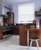 Moderne Küche mit dunklen Holzfronten und weißem Stoffrollo zwischen lavendelfarbenen Wänden