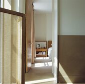 Blick an einem Paravent entlang durch offene Tür in ein weisses Schlafzimmer