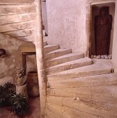 Geschwungene, rohe Steintreppe mit Statue in einer kleinen Nische und unter der Treppe