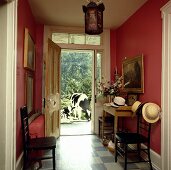 Eingangsbereich mit roten Wänden, offener Haustür und mit Blick ins Freie