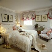 Schlafzimmer mit Spitzenbettdecke und Sessel und Jalousien mit floralem Muster