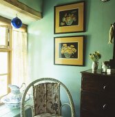 Bilder an Wand in türkisfarbener Zimmerecke und Wasserkrug auf Fensterbank