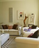 weiße Sofagarnitur und Bronzestatue im modernen Wohnzimmer