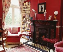 Traditionelles rotes Wohnzimmer mit Sessel vor Kamin und Fenster