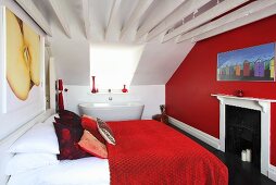 A double bed, a fireplace and a bathtub in a large bedroom with red and white walls