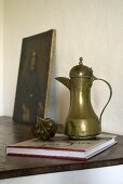A brass jug and a book on a bedside table