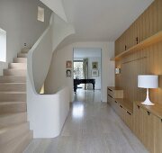Modern staircase with wood paneled walls and custom made built-in and a view through an open passage at a grand piano