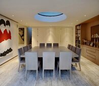 Large dining table with gray chairs under a circular skylight in a modern dining room