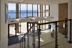 Staircase with glass balustrade and a view into a modern entry hall with glass facade and revolving door