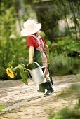 Kleines Mädchen als Gärtner mit Giesskanne und Sonnenblume