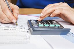 A person with a calculator and forms