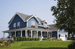 Idyllisches, pastellblaues Haus mit Veranda und gepflegtem Garten