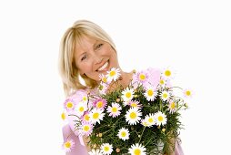 Cheerful woman holding bouquet of marguerites in her hands