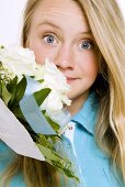 Young girl smelling bouquet of white roses