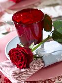 Gedeck mit rotem Glas und roter Rose