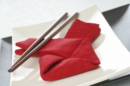 Asiatisches Gedeck mit roter Serviette und Essstäbchen