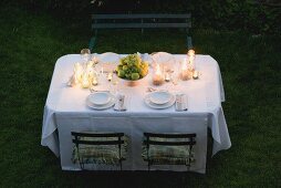 Gedeckter Tisch im Garten mit Obstschale und Windlichtern