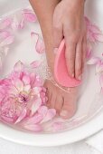 Woman washing her foot with pink sponge