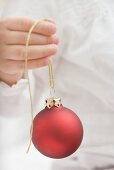 Child holding Christmas bauble with gold string