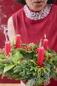 Frau bläst Kerzen auf Adventskranz aus