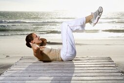 Young woman doing Sit-Ups on beach