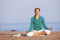 Young woman meditating on beach