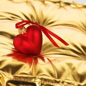 Red heart (tree ornament) on gold cushion