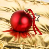 Red Christmas bauble on gold cushion
